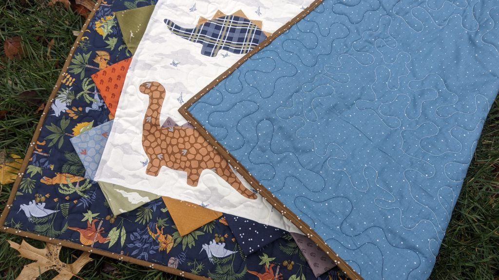 Applique dinosaur quilt with prairie point spikes and border details using the fabric collection Cretaceous