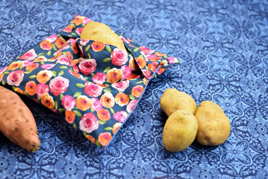 a floral potato bag for the microwave on a table covered by a blue printed piece of quilting cotton