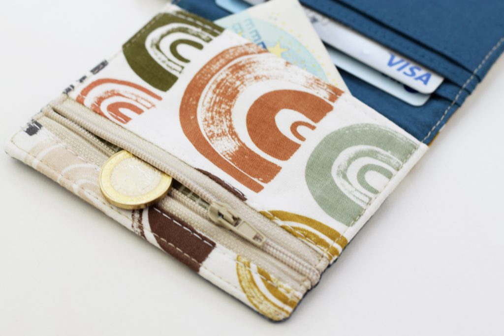 an open zipper pocket on a small wallet with a coin peeking out 
