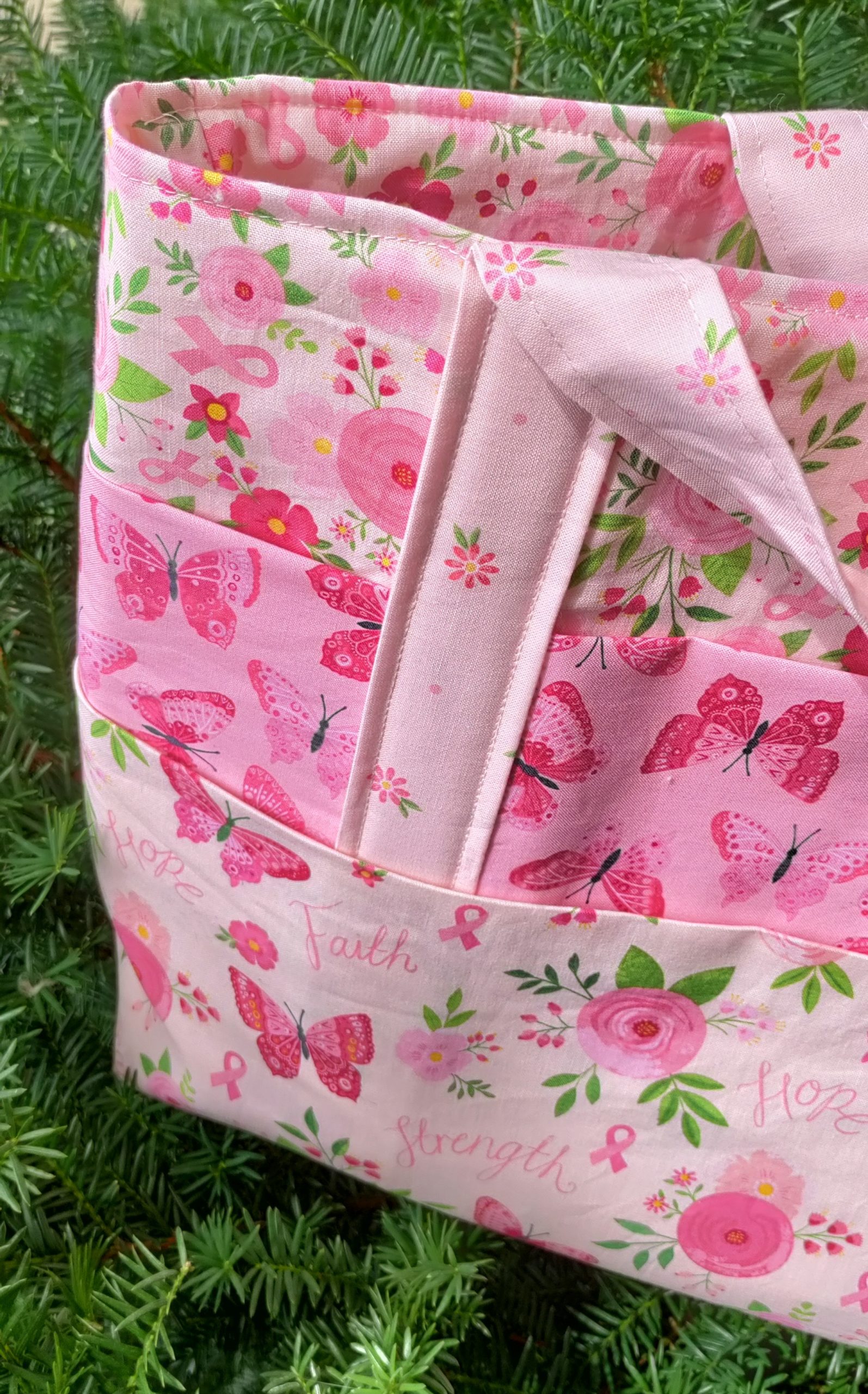 I used the Strength in Pink fabric collection, which features various shades of pink with butterflies, flowers, and breast cancer ribbons, to make a tote bag with several pockets on the outside.