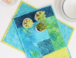aqua and green color quilted placemat with little flower pots with succulents on the placemat